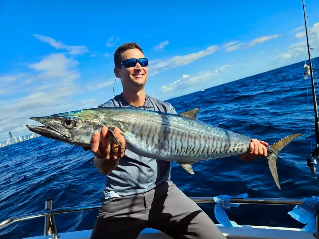 Happy guests holding their catch on a Gold Coast deep sea fishing charter with True Blue Fishing