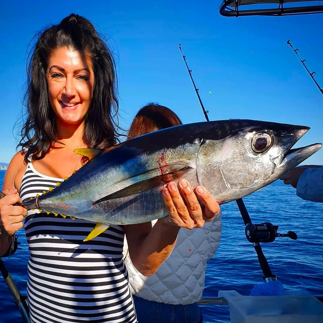 Happy guests holding their catch on a Gold Coast deep sea fishing charter with True Blue Fishing
